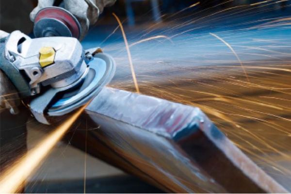 Industrial worker grinding metal surface with FUJI ORE Flap Disc on angle grinder