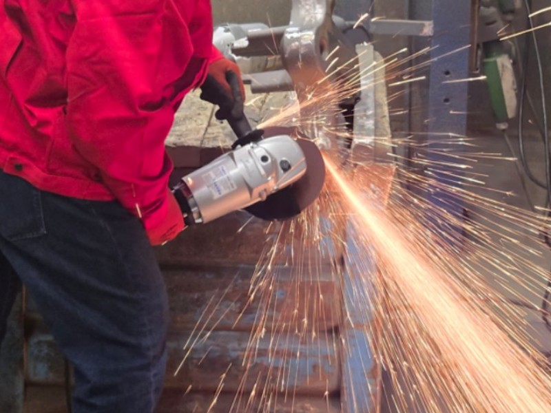 Arbeiter verwendet einen leichten 180-mm-Hochfrequenz-Winkelschleifer von FUJI f&uuml;r die Metallgussverarbeitung in einer europ&auml;ischen Gie&szlig;erei