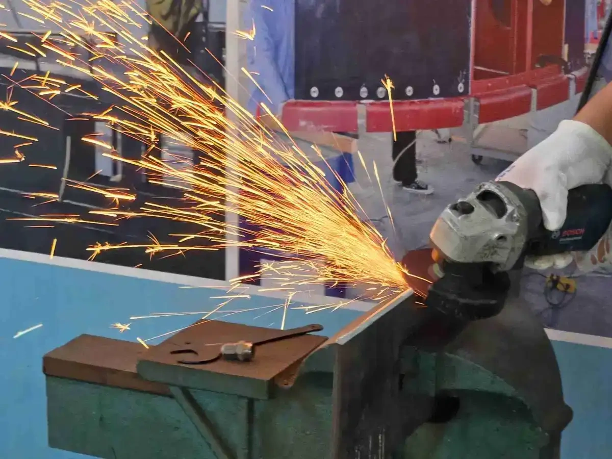 Professional worker using FUJI 115mm grinding wheel on metal surface in metal fabrication factory