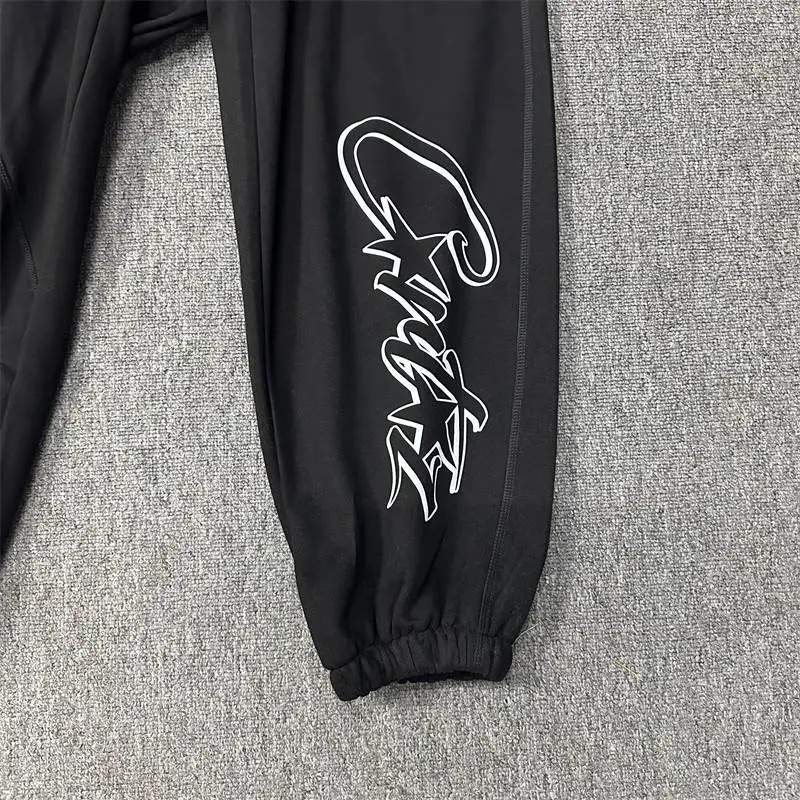 Black Corteiz jogger leg with white script graphic