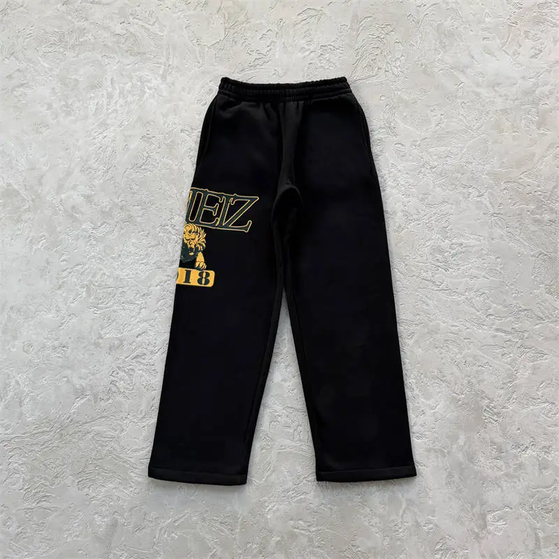 Black Corteiz Lion Varsity open hem pants with large yellow leg graphic