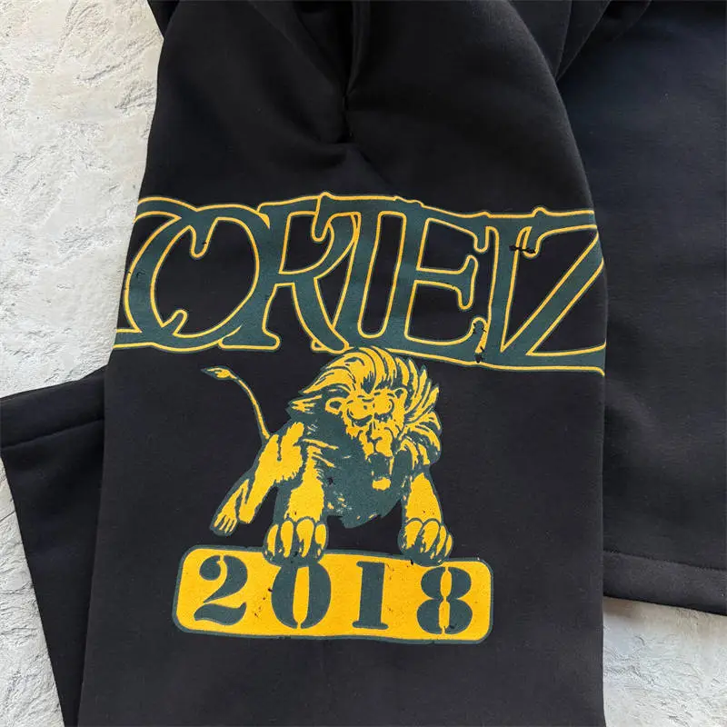 Close view of the yellow lion graphic on black Corteiz Lion Varsity pants