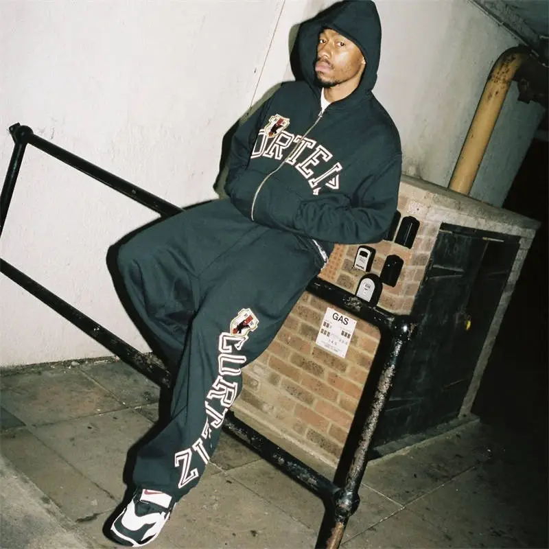 Corteiz Arch Shield tracksuit worn with relaxed open-hem sweatpants