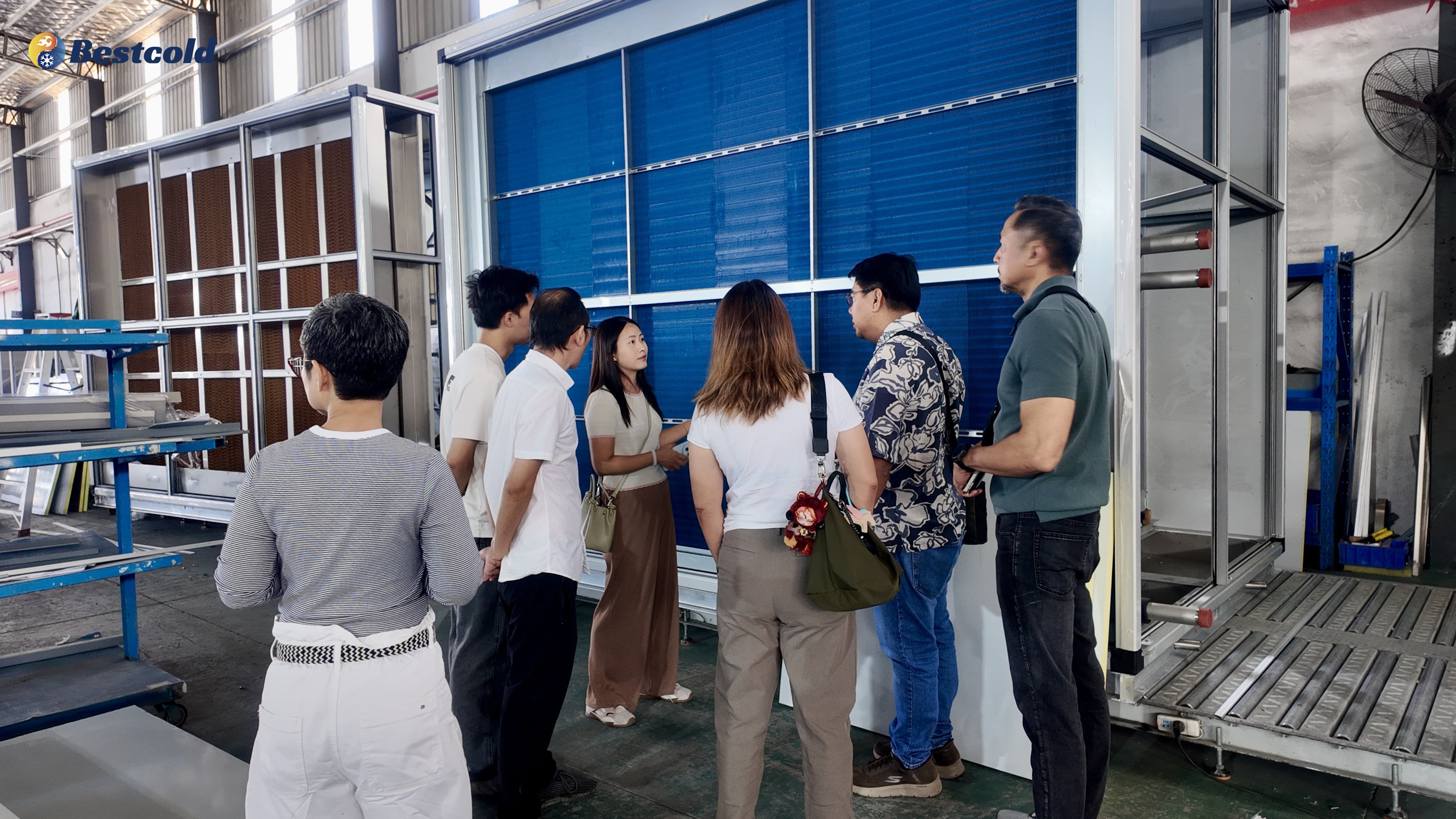 Clients inspecting commercial air handling unit with large blue fin heat exchanger coil at Bestcold HVAC factory