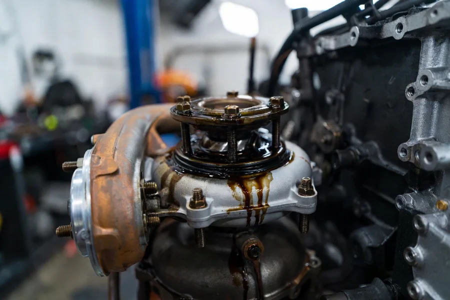 A close-up of a turbocharger with oil leakage, signifying a common issue of a failing turbocharger and the need for repairs.