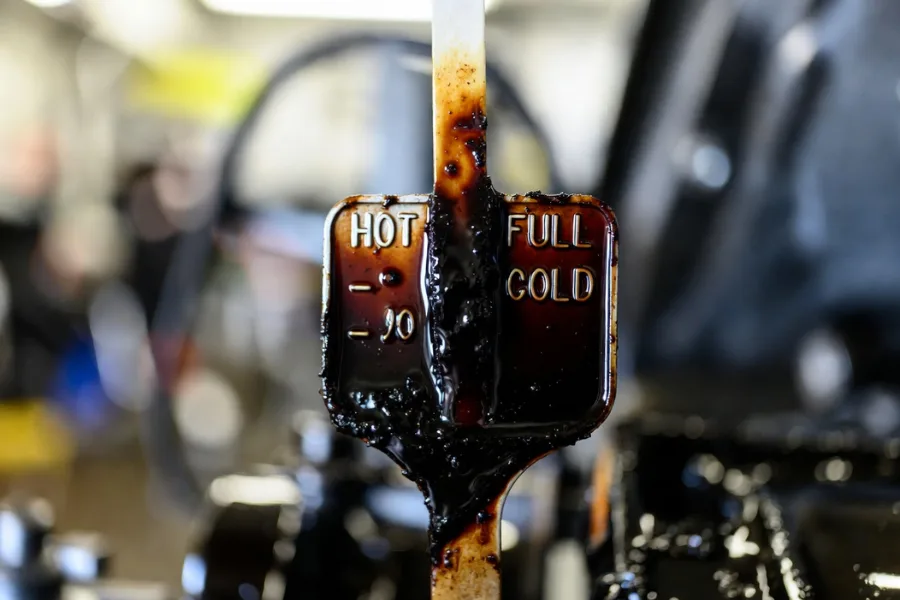 Signs your transmission fluid needs changing: dark fluid on a dipstick indicating contamination.