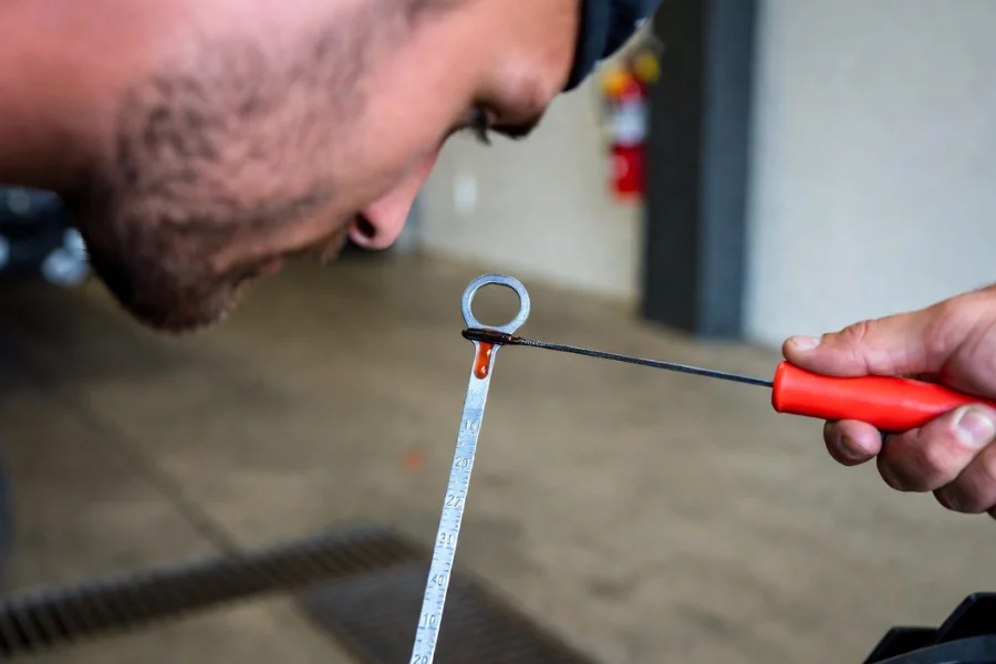 How to check transmission fluid: Mechanic using a dipstick to check fluid condition and level.