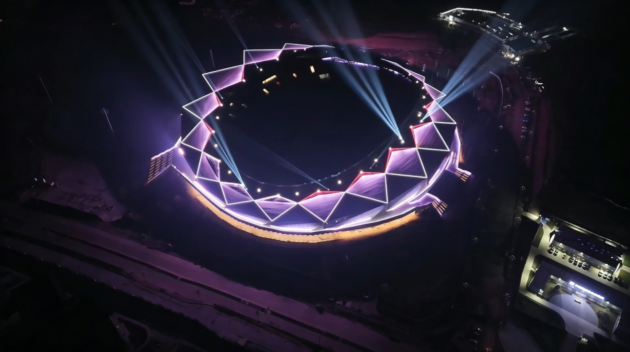 Top-down aerial night view of Guang'an Olympic Sports Center with purple dynamic facade lighting