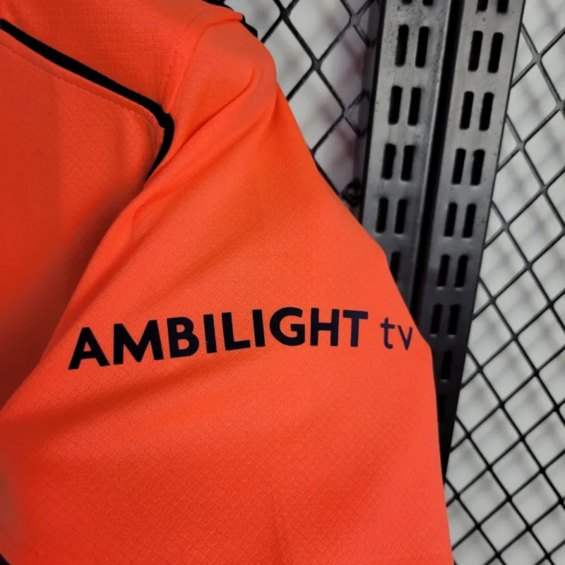 2025-26 Barcelona second away jersey sleeve detail featuring AMBILIGHT TV sponsor logo on bright orange fabric with textured design