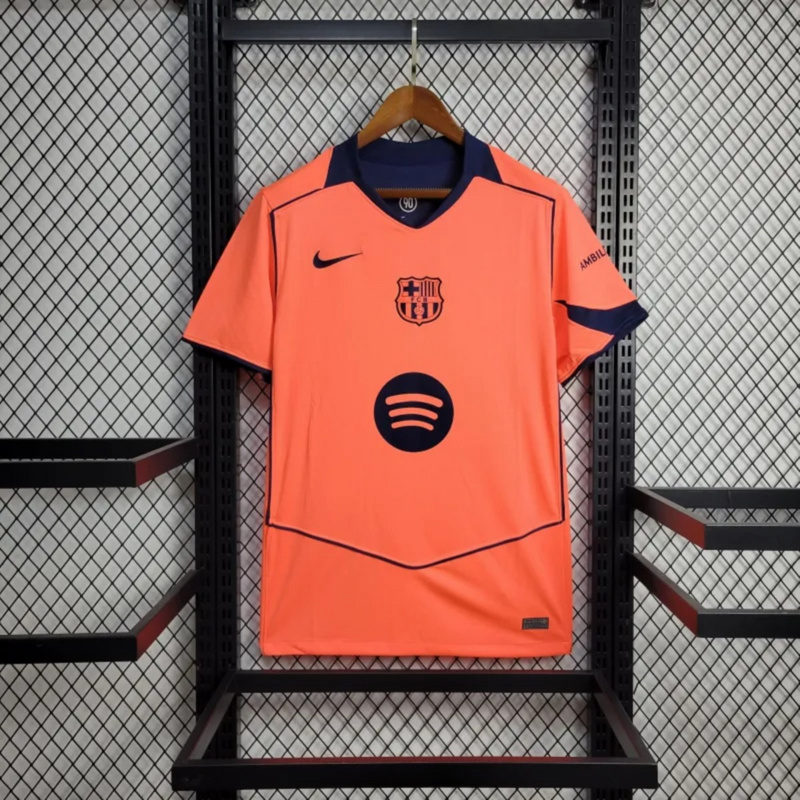 Full view of the 2025-26 FC Barcelona Second Away Jersey Fan Version in bright orange with navy details, Nike logo, Spotify sponsor, and embroidered FCB crest.
