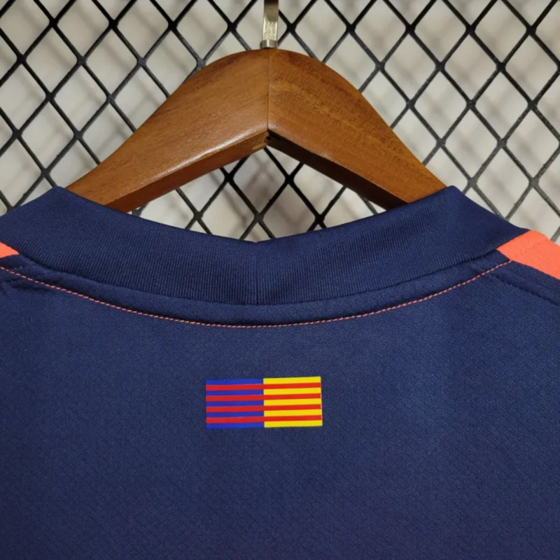 Back collar of the 2025-26 Barcelona second away jersey showing Catalan and club color flag graphic, with navy fabric and orange stitching.