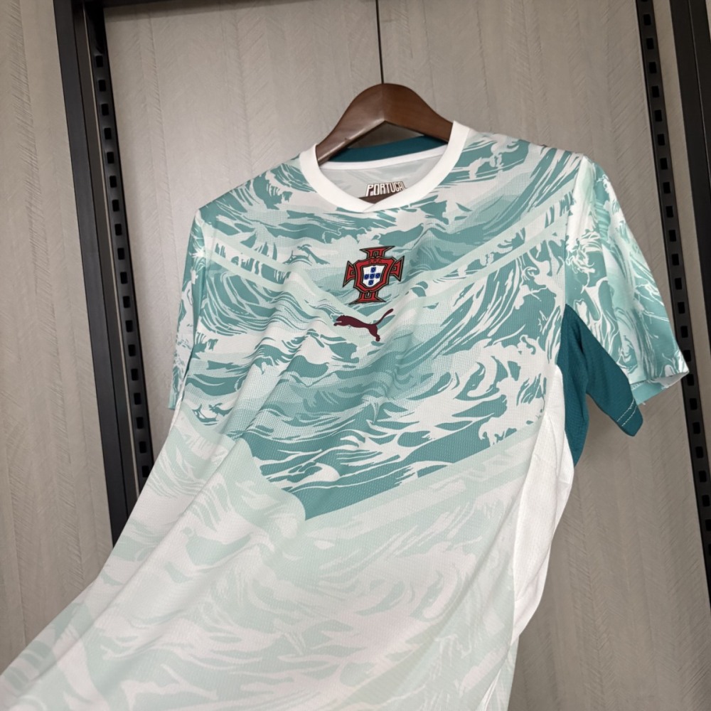 Angled front view of the Portugal 2026 World Cup away jersey with teal ocean-wave graphic pattern, Portugal national team crest at the center chest, and Puma logo below.
