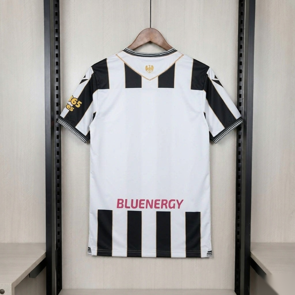 Udinese Calcio 2026-27 home shirt back - a broad white V-shaped yoke outlined in gold on the upper back carrying the gold Patriarchal Eagle of Friuli, black and white stripes across the shoulders and flanks, a plain white central panel left clear for a name and number, four black stripes across the lower back with the pink-magenta BLUENERGY wordmark outlined in white above a striped hem, and the gold bet365 Scores mark low on the wearer's left sleeve; no name and no number