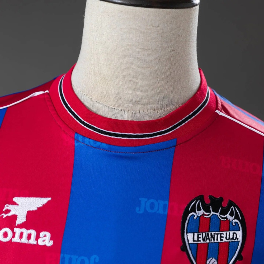 Close view of the collar on the Levante 1999-00 shirt - a crimson ribbed crew collar whose edge carries a fine white line, a black line and a second fine white line, with the tone-on-tone maker's lettering visible in the fabric beside it