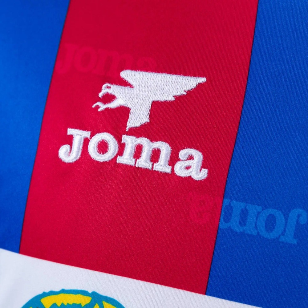The maker's mark on the Levante 1999-00 shirt - a white embroidered stylised winged creature above a lowercase wordmark, sitting on a crimson stripe between the shoulder seam and the chest