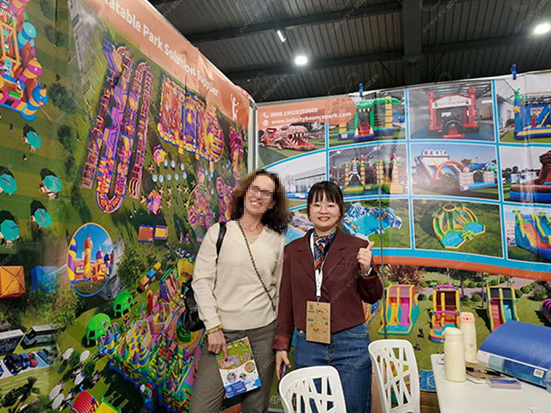 Business manager consulting with client about inflatable bouncy castle and combo solutions with product catalogs at SETT 2025