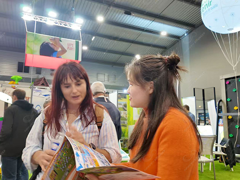 Professional exchange between Infinity Bounce Park representative and client discussing inflatable products at SETT 2025