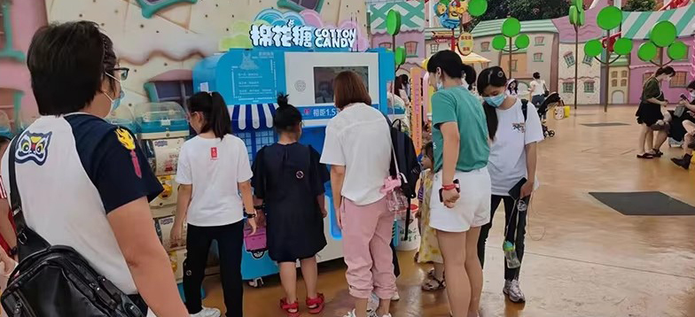 Automatic cotton candy vending machine beside playground rides