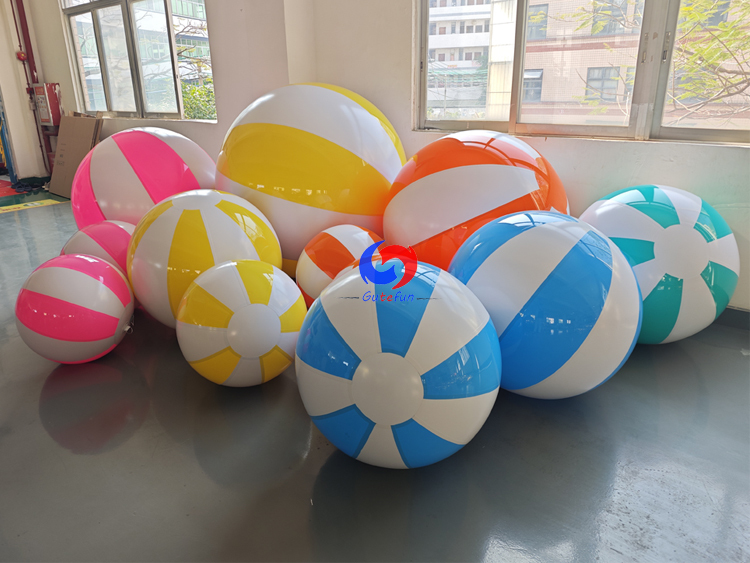 Glossy giant yellow‑white striped inflatable beach balls in mixed sizes