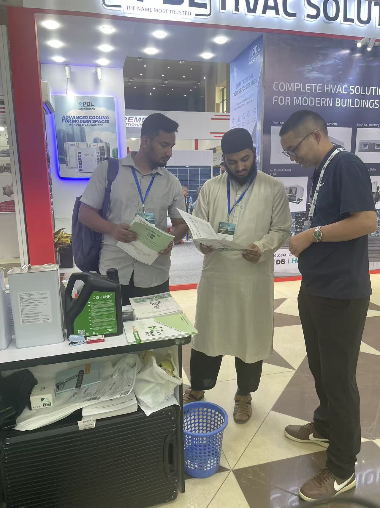 Exhibition visitors reviewing QISHANR refrigeration oil literature