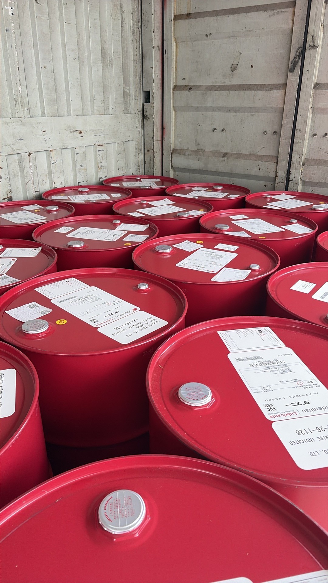 Photograph taken by the customer of a shipment of red Idemitsu drums on pallets inside a container, each drum top carrying a printed label