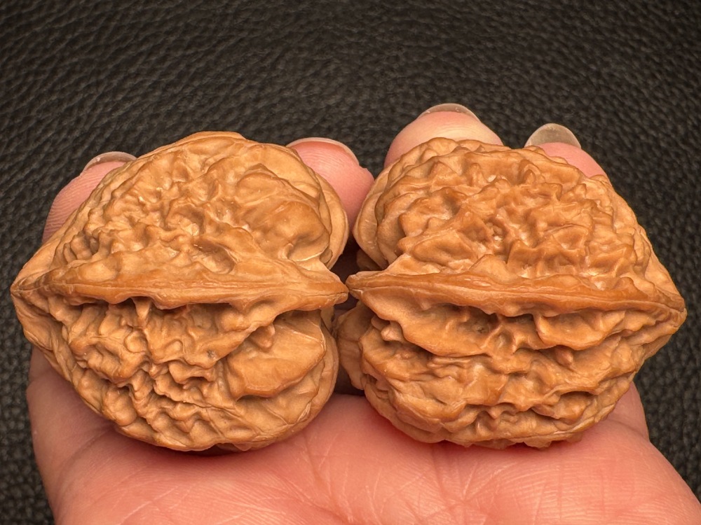 Chinese intangible cultural heritage cultural items featuring walnut nuts and wild oxen running towards a triangular shape. Hand-held pieces for health preservation and excellent therapeutic items.