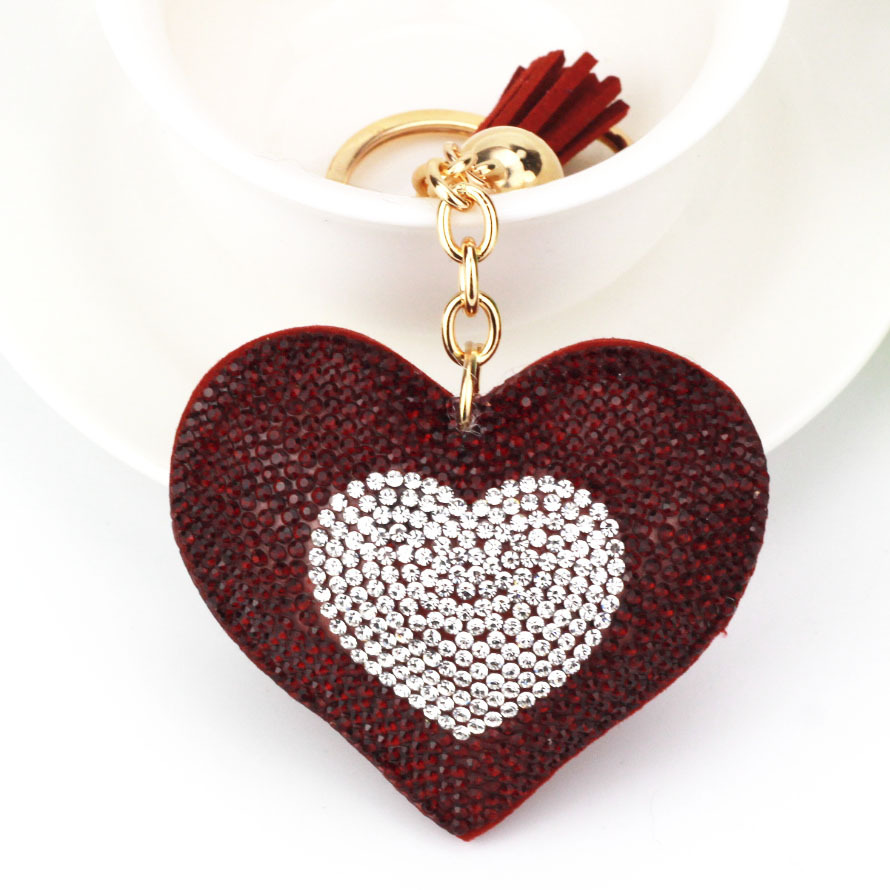 Wholesale two-tone heart-shaped keychains with rhinestone embellishments and heart-shaped tassels for bags and car hangings.