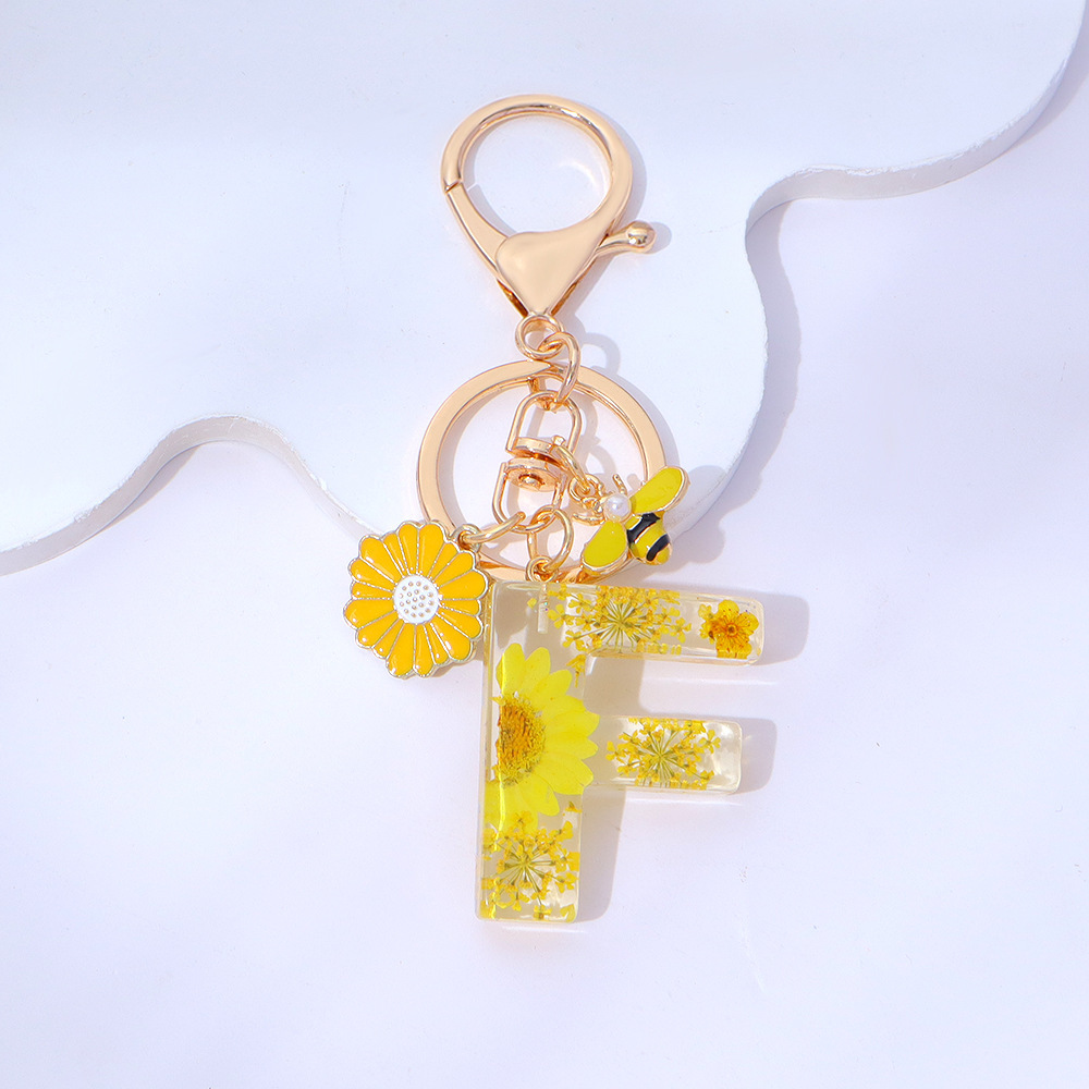 Wholesale yellow daisy epoxy resin letter keychains, bee pendants, bag charms, personalized jewelry, and gift ornaments.