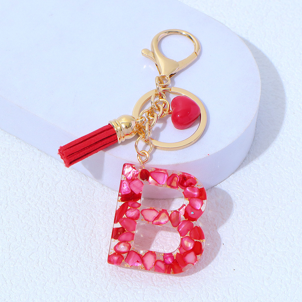 Wholesale red stone-filled letter keychains, resin heart tassel pendants, bag charms, party gifts.