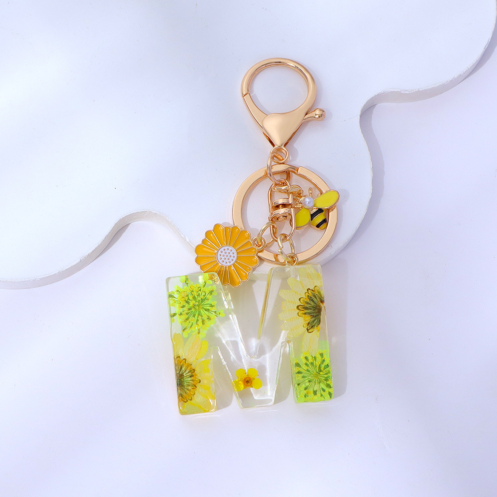 Wholesale yellow daisy epoxy resin letter keychains, bee pendants, bag charms, personalized jewelry, and gift ornaments.