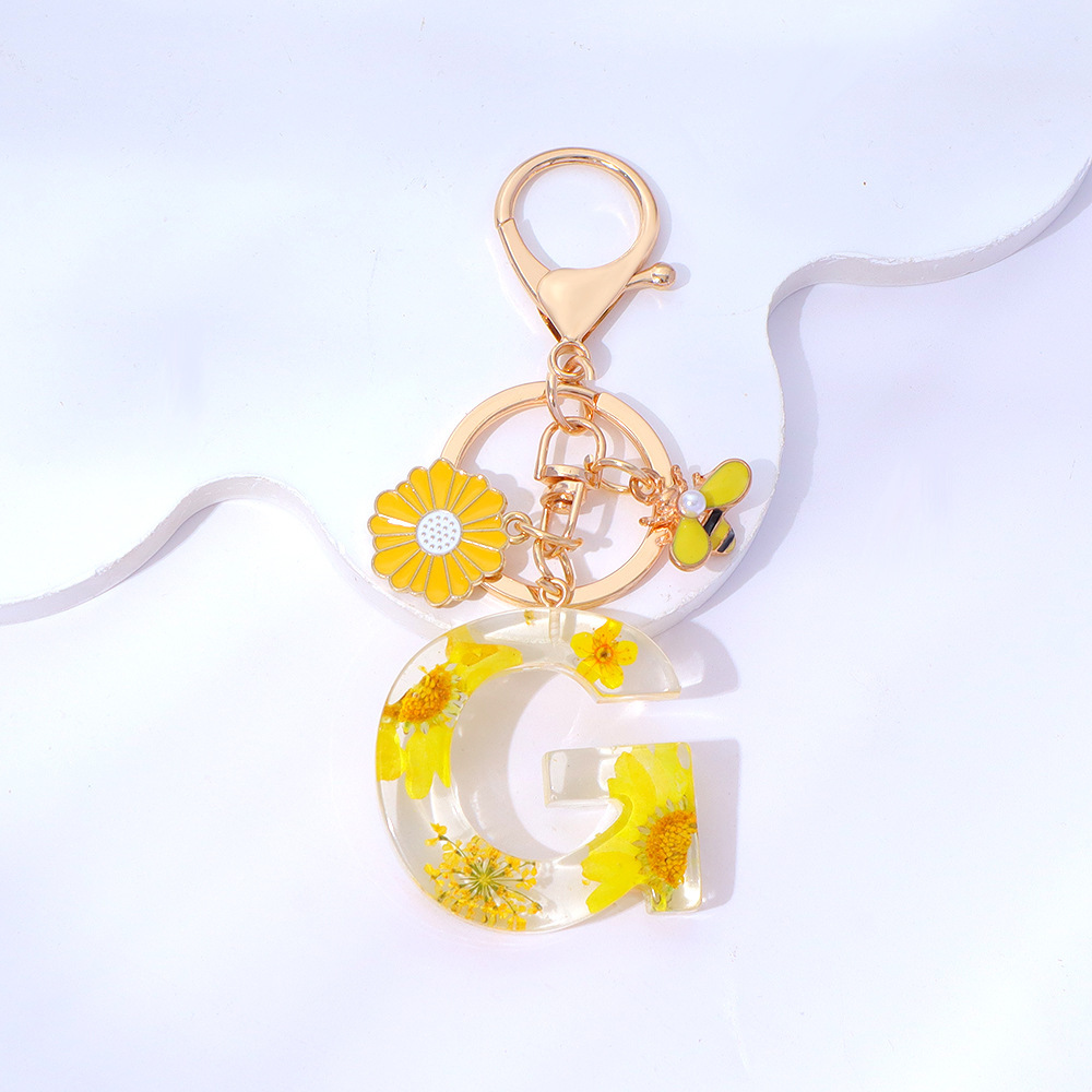 Wholesale yellow daisy epoxy resin letter keychains, bee pendants, bag charms, personalized jewelry, and gift ornaments.