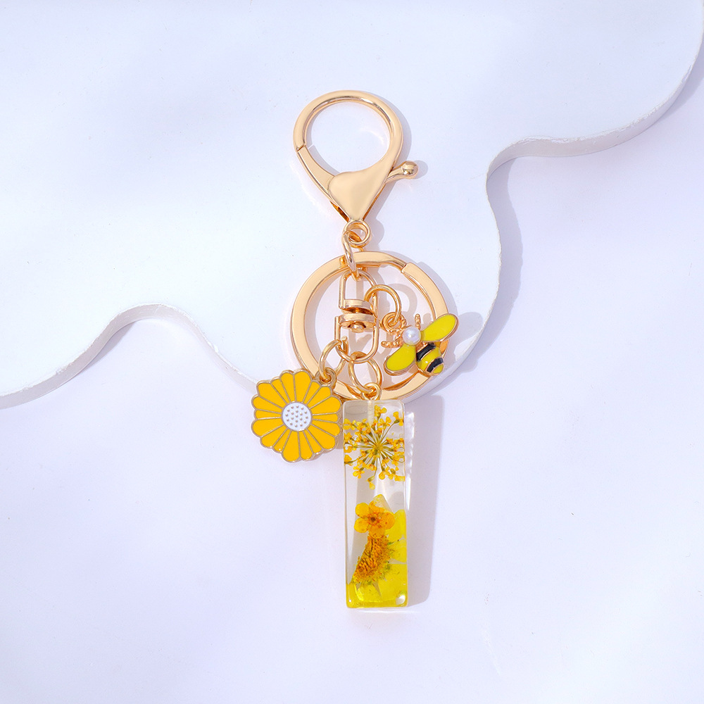 Wholesale yellow daisy epoxy resin letter keychains, bee pendants, bag charms, personalized jewelry, and gift ornaments.