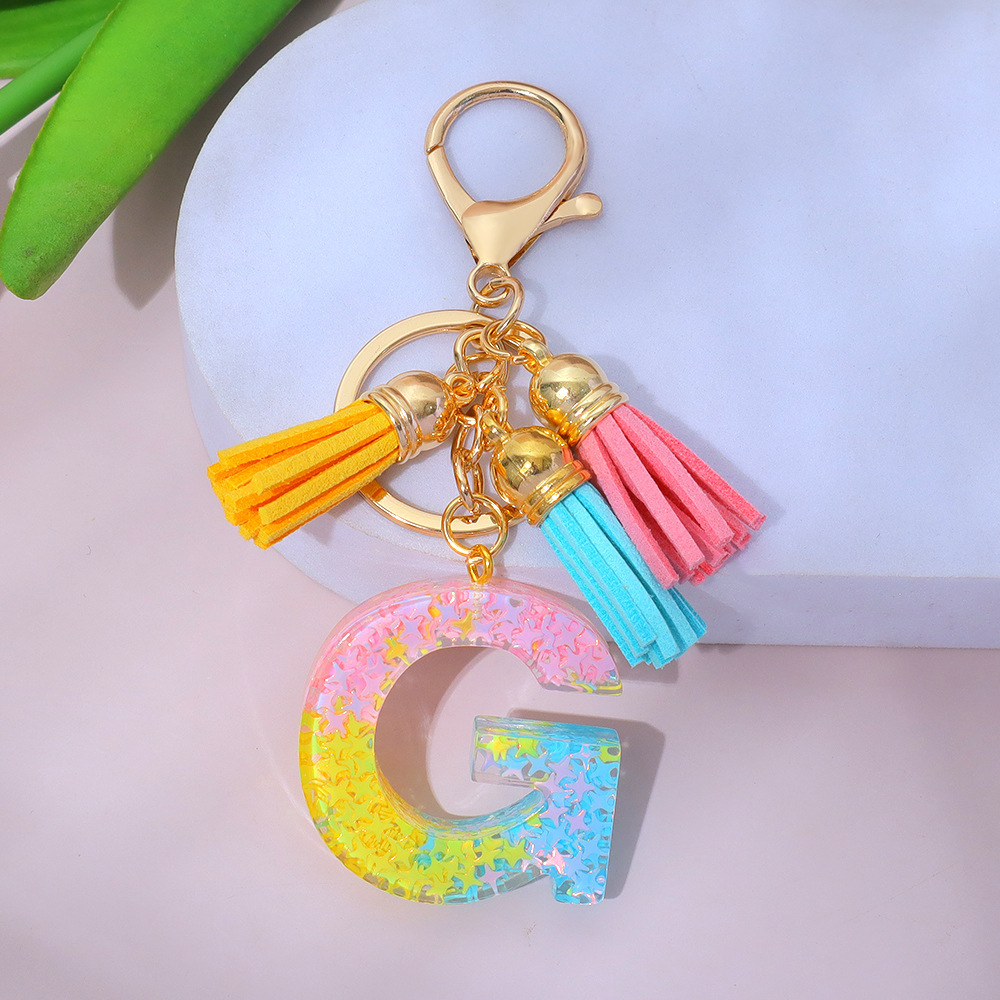 Wholesale star-studded sequin-filled letter keychains, tassel resin pendant keychains, and souvenir decorations for women's backpacks.