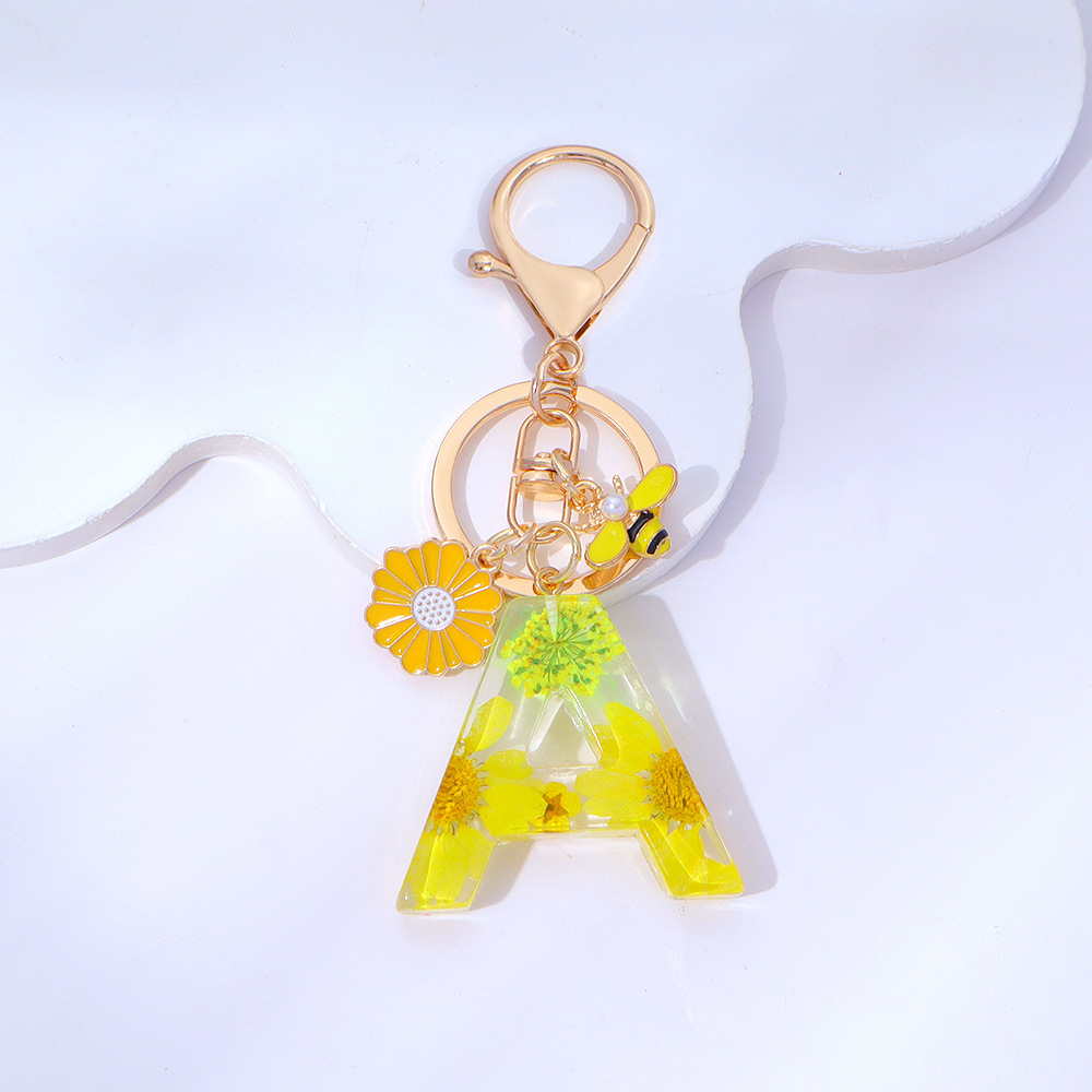 Wholesale yellow daisy epoxy resin letter keychains, bee pendants, bag charms, personalized jewelry, and gift ornaments.
