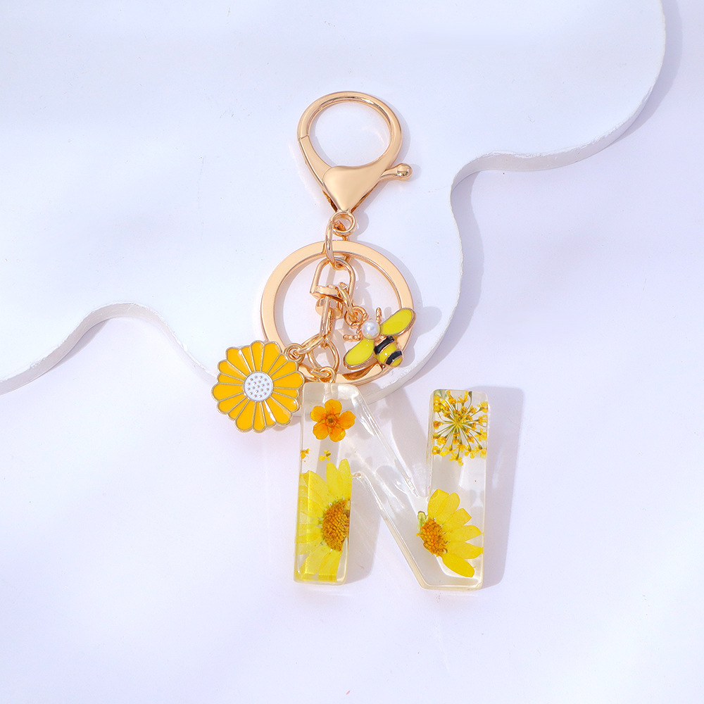Wholesale yellow daisy epoxy resin letter keychains, bee pendants, bag charms, personalized jewelry, and gift ornaments.