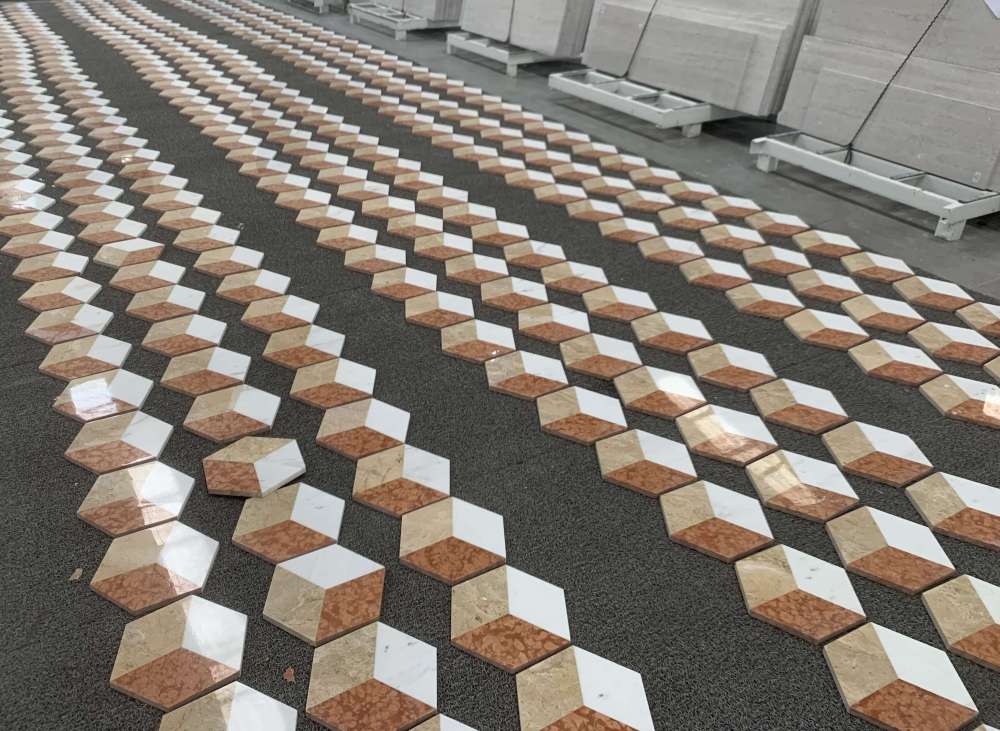 Factory dry lay inspection process of polished hexagon marble tiles to ensure color consistency and perfect 3D pattern alignment before packaging.