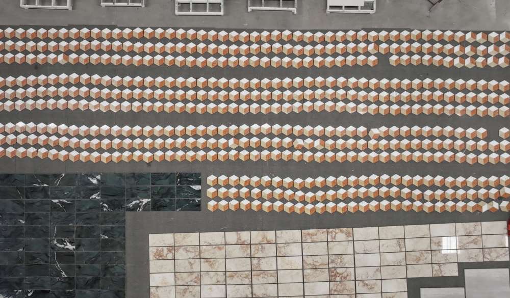 Aerial top-down view of bulk hexagon marble tiles laid out in the factory, displaying the consistent geometric 3D cube pattern across a large floor area.