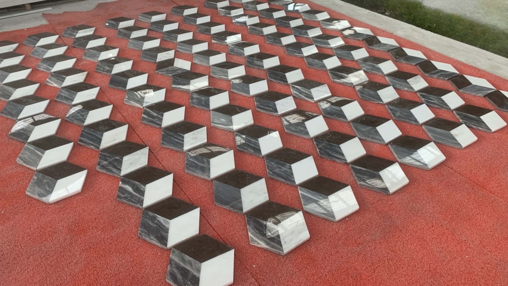 Large quantity of hexagon marble tiles displayed in factory inventory, showing consistent white, gray, and black natural stone colors ready for shipping.