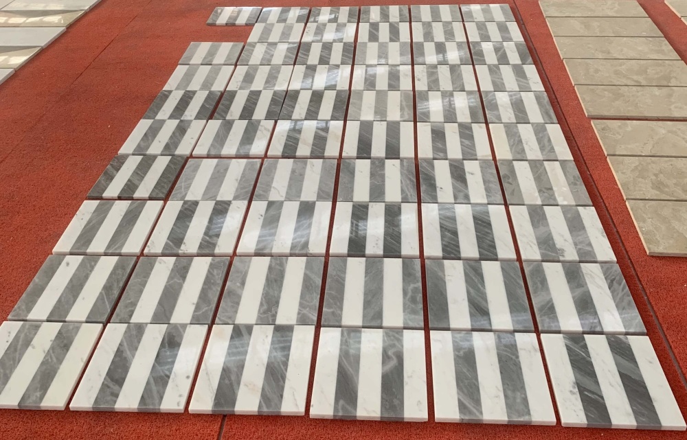 Side view of mass-produced 12x12 waterjet marble tiles displaying high-gloss polished finish and uniform natural stone veining.