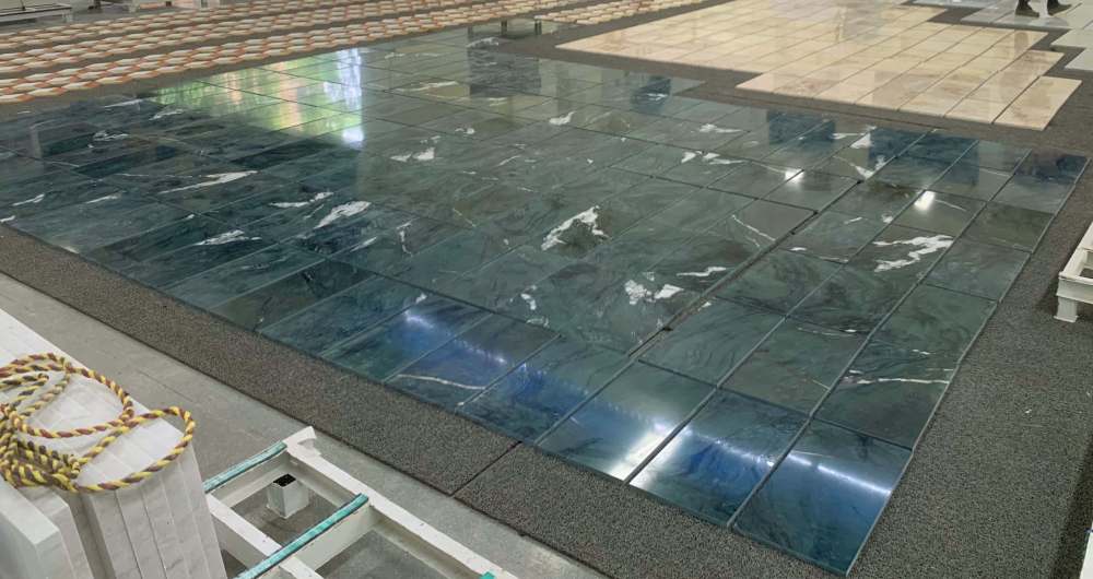 Factory dry lay inspection of Diamond Green polished marble tiles, showcasing the high-gloss reflective surface and consistent emerald color quality for large projects.