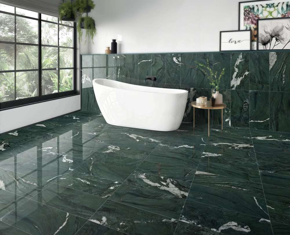Seamless floor-to-wall installation of 12x24 Diamond Green polished marble tiles in a bright bathroom, showcasing the high-gloss reflective finish.