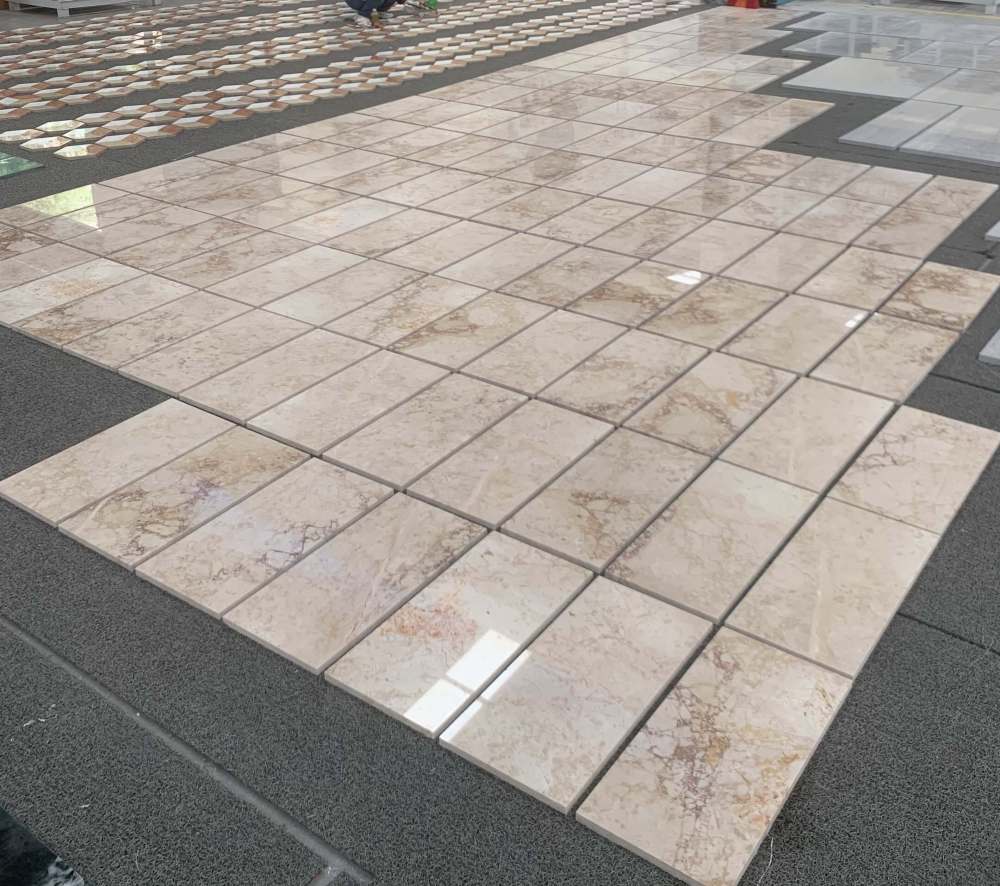 Perspective view of Diamond Pink marble tiles arranged in a factory dry lay, showcasing the high-gloss polished finish and consistent quality across a large batch.