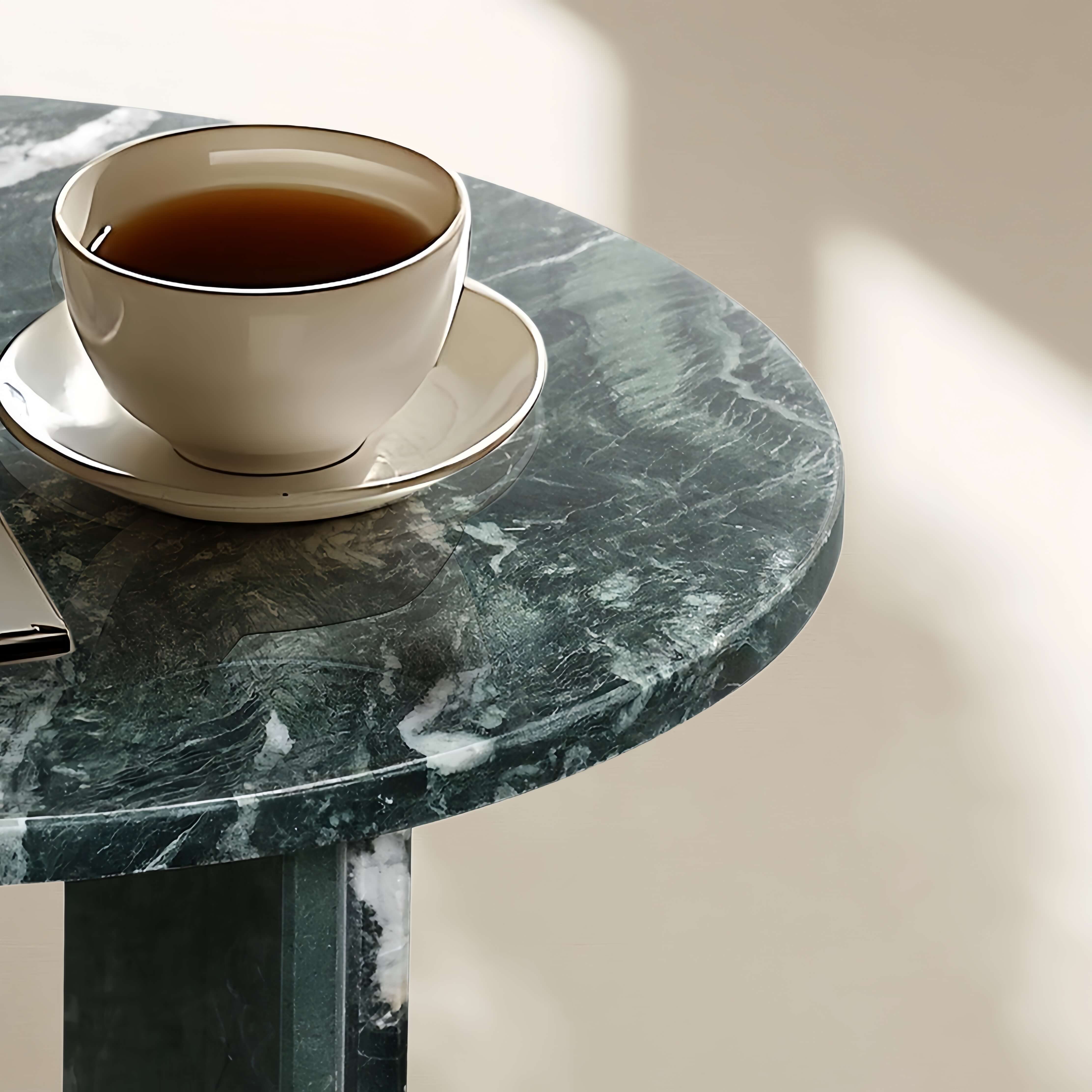Lifestyle close-up of a coffee cup on the glossy green marble table surface, highlighting the stone's natural texture and reflectivity.