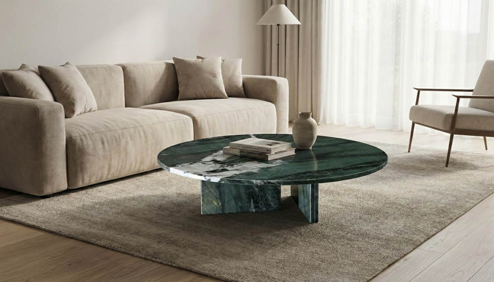 A 90cm Diamond Green marble round coffee table centered in a minimalist living room, featuring a cross-base design and placed on a beige rug.