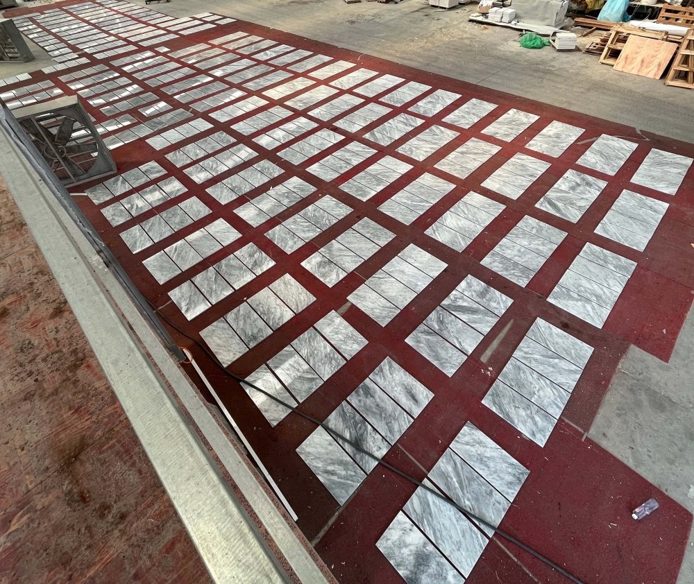 Large scale factory production and dry-lay inspection of premium Carrara Gray polished marble tiles, ensuring high-quality natural stone consistency.