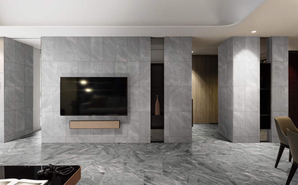 Luxury living room featuring a stunning TV accent wall with 12x24 Carrara Gray OL textured tiles, perfectly complementing the polished marble floor tiles.