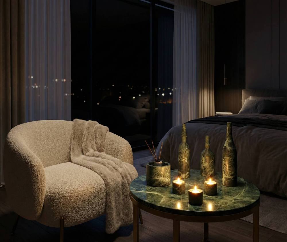 Lit dark green marble tealight holders and vases creating a warm, luxurious night glow in a modern contemporary bedroom.