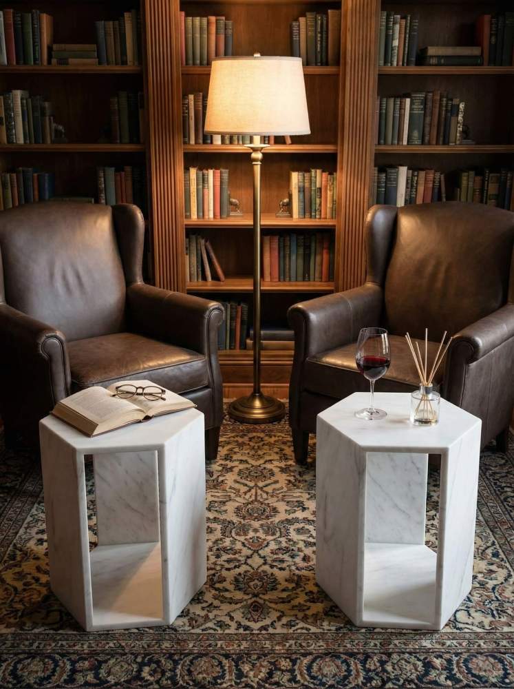 A pair of unique Snow Mountain white marble pedestal tables in a classic home library with leather armchairs, showcasing their timeless elegance.