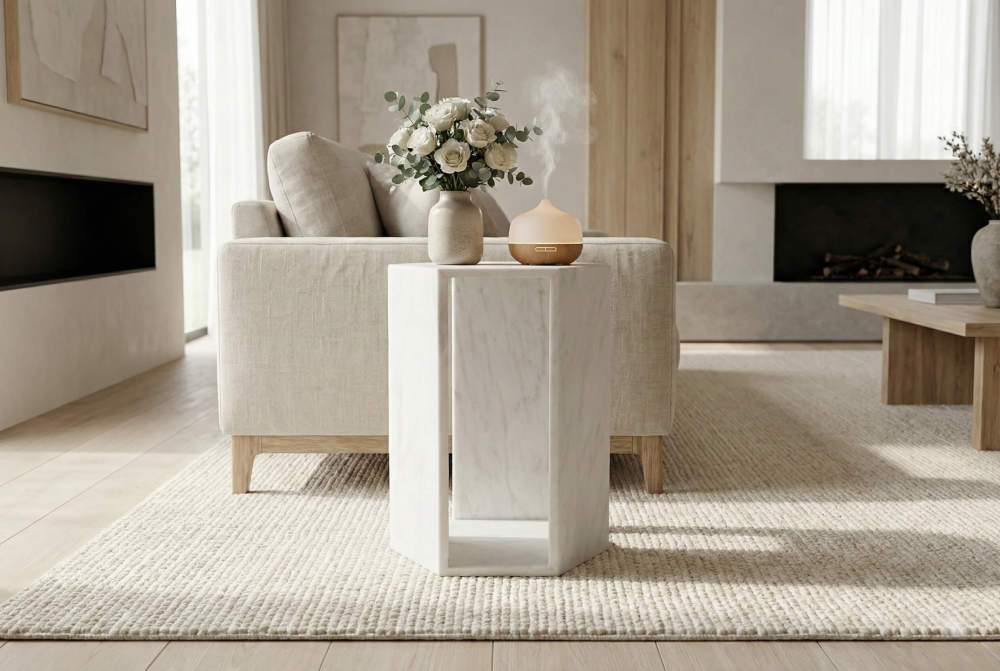 Minimalist living room setting featuring the honed white marble end table beside a modern sofa, beautifully displaying an aroma diffuser and fresh flowers.