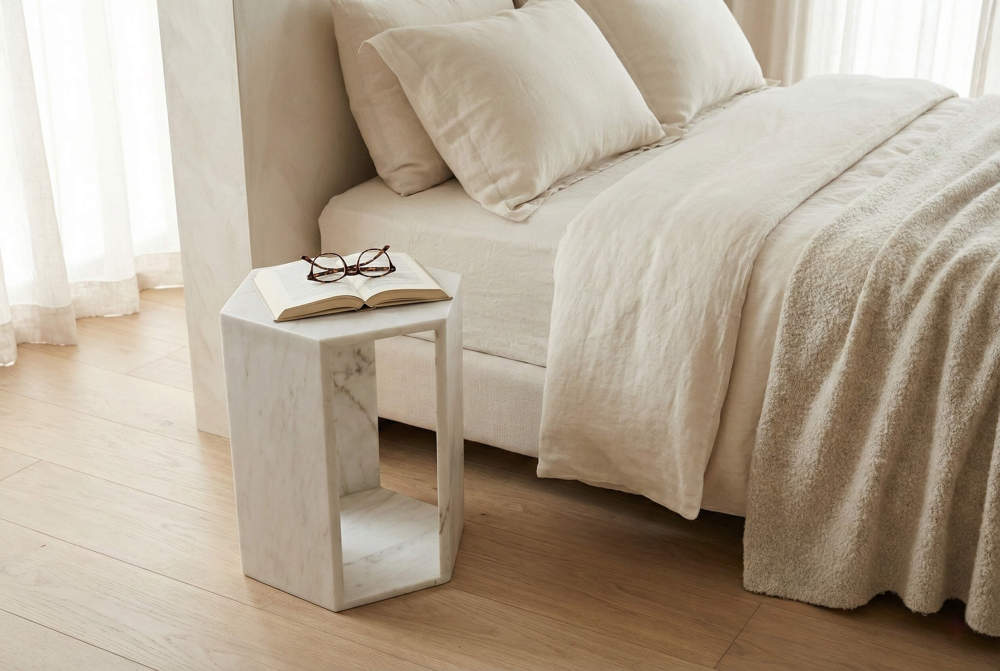 The versatile white marble hexagonal table functioning as a sophisticated bedroom nightstand. In stock and ready to ship from our US warehouse.